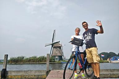 Una coppia in posa che saluta, felici con una bici che li divide e sullo sfondo Haarlem