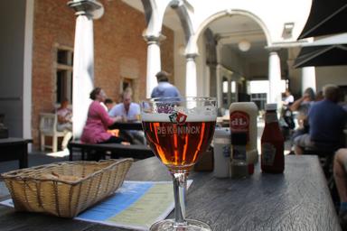 Bar tipico belga. sul tavolino in primo piano, una birra, un cestino e salse varie